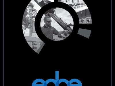 A black cover features the word "edge" in blue at the bottom. Above, a circular design contains black-and-white photos of smiling men working with industrial equipment. Text at the bottom lists topics like VFD Impact and Seed Treatment for Corn.
