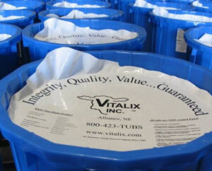 Several blue tubs are lined up, each covered with a white lid displaying "Integrity, Quality, Value... Guaranteed" and the Vitalix Inc. logo along with contact information and product details.