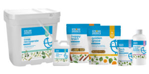 A lineup of poultry health products from Strong Animals, including a large white tub, bottles, and resealable pouches labeled Coop Recuperate, Happy Tract, Golden Graze, Flock Fixer, and Chicken E-lixir.