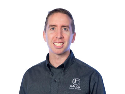 A man with short brown hair wearing a dark button-up shirt with the "RALCO Animal Nutrition" logo, smiling against a plain white background.