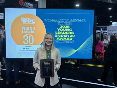 A woman smiles while holding a plaque in front of a display that reads "Congratulations to the 2025 Young Leaders Under 30 Award Winners" at an event. The backdrop also features the IPPE Young Leaders logo.