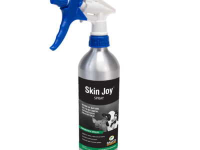 Skin Joy Spray by Ralco comes in a silver bottle with a blue and white trigger, green accents, and features a cow image on the label.