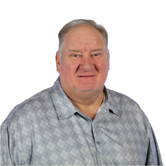 A middle-aged man with short, light-colored hair wearing a gray plaid button-up shirt, smiling and posing against a plain white background.