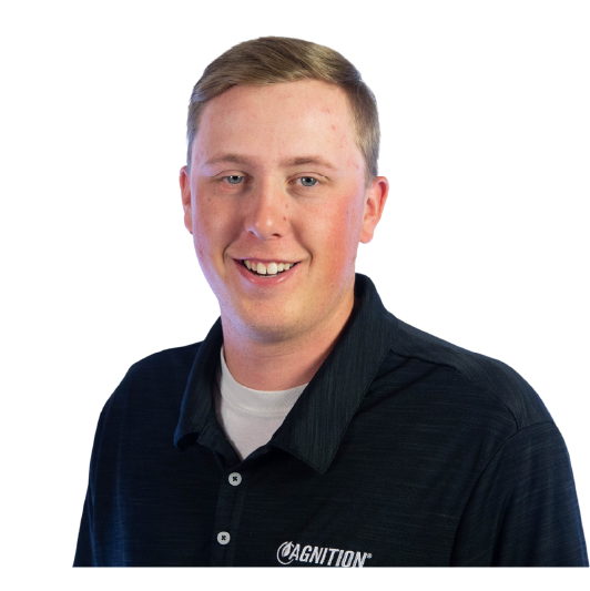 A man with short light brown hair wearing a black collared shirt with a white "CAGNITION" logo on it, smiling at the camera against a plain white background.