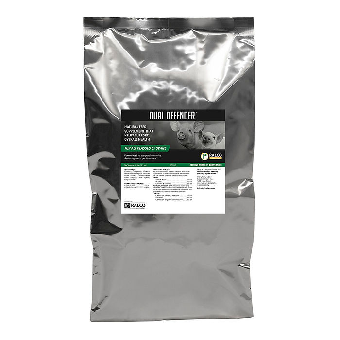 A silver bag labeled "Dual Defender," a natural swine feed supplement, features livestock images and a green-and-white information label.