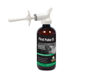 A brown bottle labeled "First Pulse D" with a white oral applicator, designed for piglets as an oral drench to support appetite and vigor. The label shows a piglet image and features Ralco branding.
