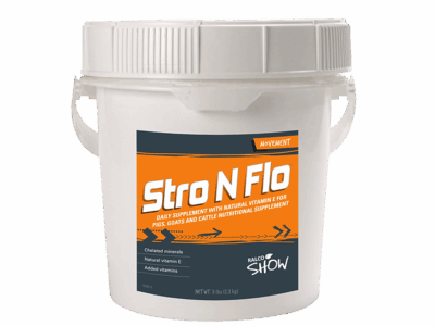 A white plastic bucket labeled "Stro N Flo" with an orange, black, and white label contains a daily supplement for pigs, goats, and cattle. The bucket features a handle and a secure lid.