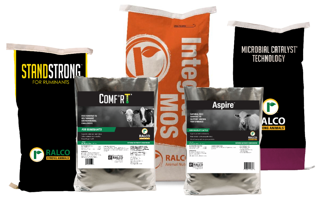 Several bags of Ralco animal nutrition products, including StandStrong, Comfort, Aspire, Integra MOS, and Microbial Catalyst Technology, are displayed upright with visible product labels and branding.