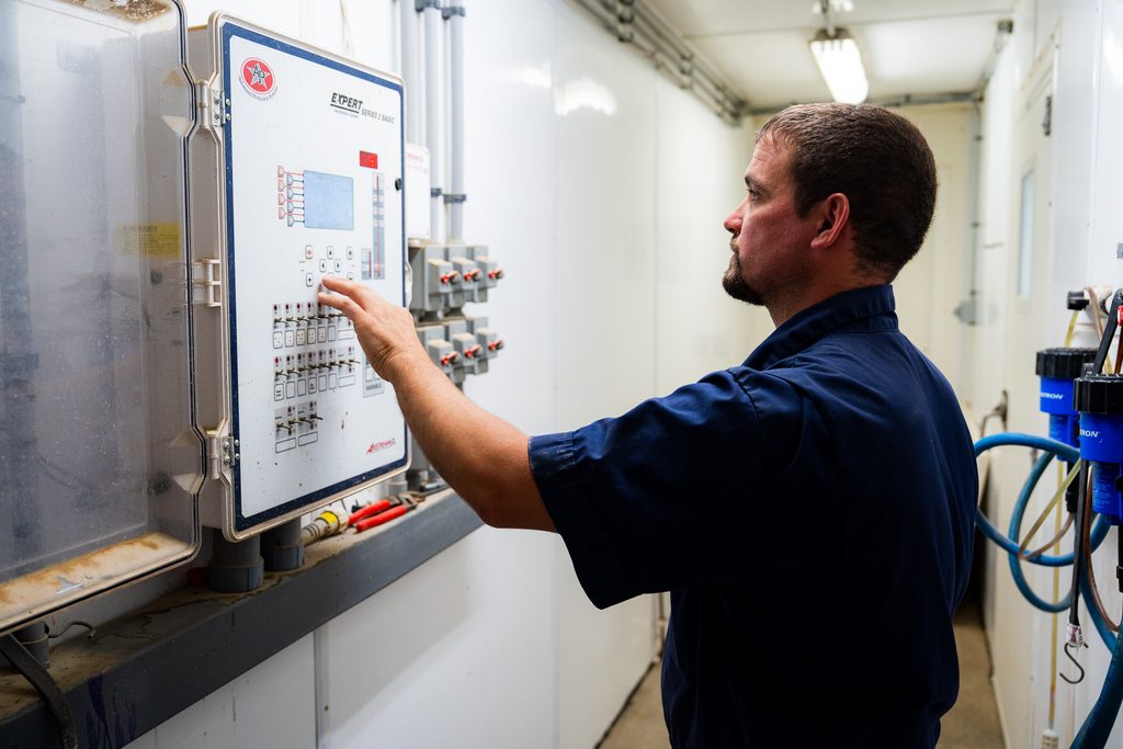 swine employee in a pig barn checking their electrical and control panel settings